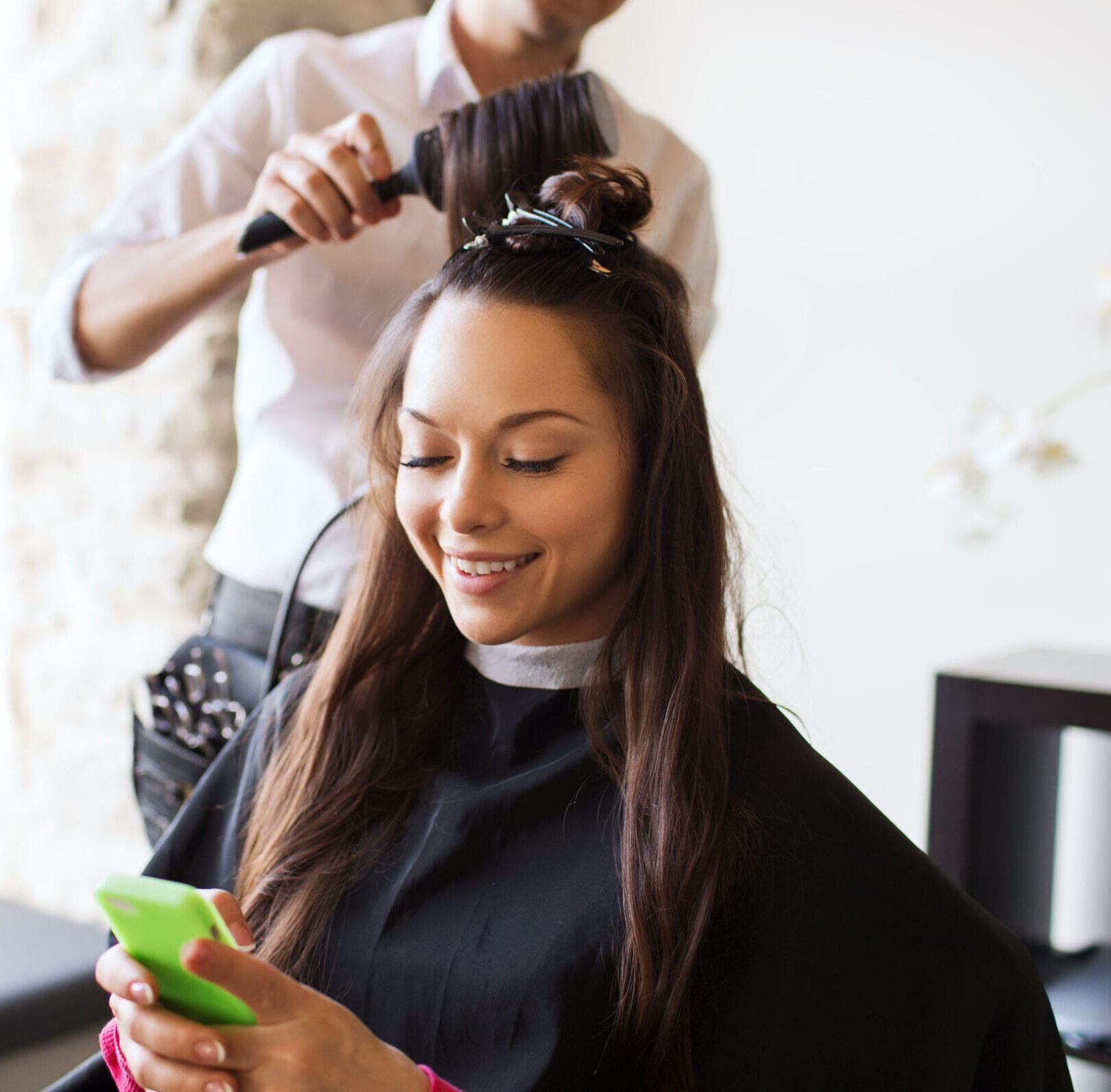 38817836_l happy young woman with smartphone and hairdresser making hair styling at salon